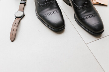 A pair of a executive man shoes and a brown watch with empty space.