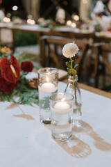 A beautiful bouquet of flowers, glass of candle and glass of flower arranged on the table, for romantic dinner or wedding reception.