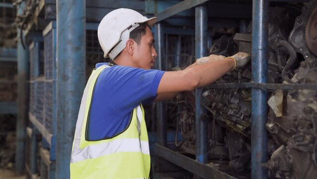 Old car alternators on shelf. Engineer man and Foreman wearing safety helmet standing at recycling yard of old industrial vehicle.