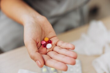 A woman with a cold with pills is treated at home chooses which drugs to take and self-medicates, checks the expiration date while sitting on the couch at home