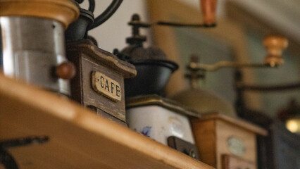 Close-up shot of antique coffee grinding machines. Vintage wooden machines on a shelf of an old bar illuminated by daylight.