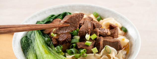 Beef noodle soup. Taiwanese famous food in a bowl on wooden table.