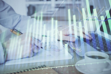 Multi exposure of stock market graph with man working on laptop on background. Concept of financial analysis.