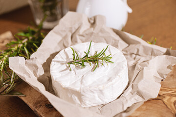 Delicious italian Camembert cheese. Fresh Camembert cheese with rosemary on a food paper. Tasty...