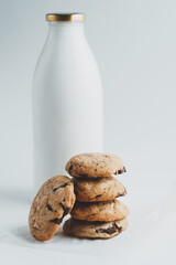 Homemade cookies with pieces of chocolate on the background of a bottle of milk on a white background