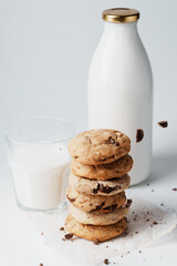 Homemade cookies are sprinkled with chocolate on the background of a bottle of milk and a glass