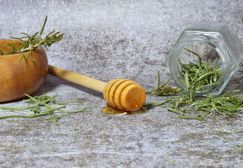 Close up. Honey and herbs from the woody stems of rosemary, on a stone background, along with a...