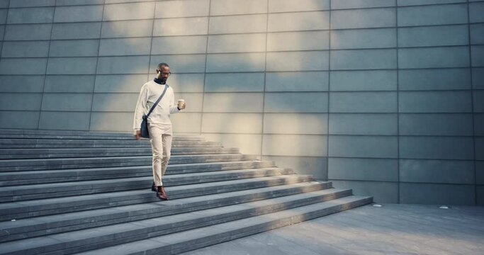 Businessman, coffee and walking to work outdoor, commute and travel to job or appointment in New york city. Young male, entrepreneur and cup for traveling, stairs and international trip in urban town