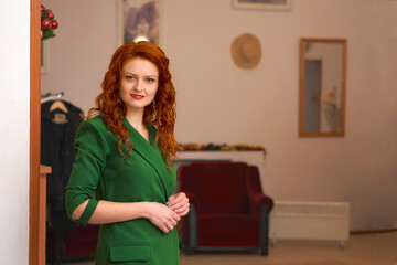 Young red haired smiling woman in a green in the lobby of the hotel restaurant 