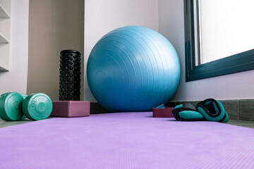 background with a yoga mat, pilates ball, weights, elastic bands.