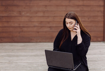 Young brown hair woman with laptop and smart phone computer sitting on wood floor - Powered by Adobe