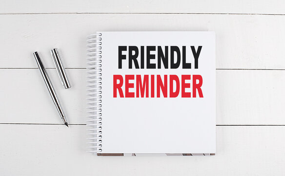 FRIENDLY REMINDER text written on notebook on the wooden background