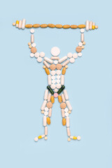 Shape of a bodybuilder with a barbell made of pills on a blue background