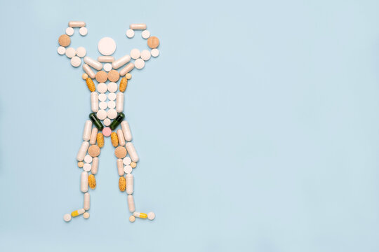 Shape of bodybuilder made of pills on blue background