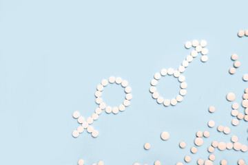 Medical pills in female and male symbol shape on a light blue background. Concept female and male health, contraception,  pregnancy, fertility