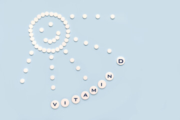 Pills in the form of the sun with rays and the word vitamin D on a blue background. VITAMIN D word...