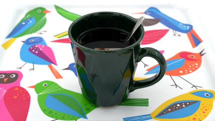 A cup of brewed bergamot tea with a green mug and teaspoon