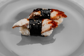 Two portions of sushi with shrimp and eel on a gray plate