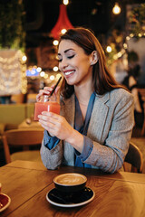 Beautiful young adult woman sitting in a nice restaurant or coffee bar and enjoying in fresh good coffee drink.