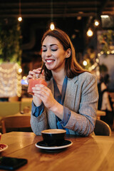 Beautiful young adult woman sitting in a nice restaurant or coffee bar and enjoying in fresh good coffee drink.