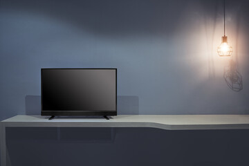 Flat LCD television on wood table  and light bulb in the living room with dark gray wall