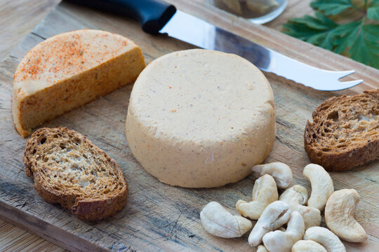 Vegan cheeses and toasted bread on a wooden board and knife.