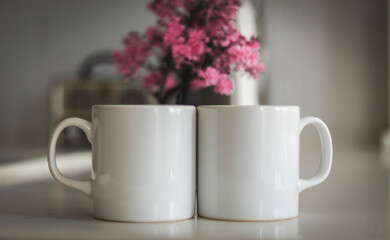 Two mug mockup on kitchen counter. Sublimation white blank two mug mock up for e-commerce sellers and designers and a beautiful pink flower in the background to increase sales for cup brand