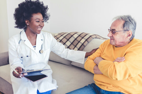 Nurse Talking During Visit To Old Patient Grandfather. Caring Caregiver Hold Hand Of 70s Senior Elderly Man Having Pleasant Conversation, Satisfied Men Receiving Support And Care From Carer Concept