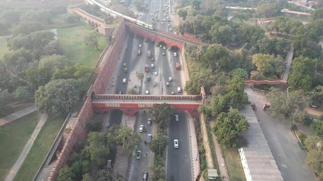 Aerial Drone shot of a Indian railways train crossing a bridge over a busy road at Red Fort in New Delhi India 