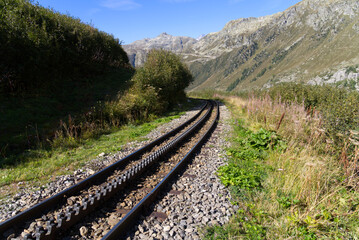 Fototapeta premium Cog wheel railway tracks of historic narrow gauge railway at Swiss mountain pass Furkapass on a sunny late summer day. Photo taken September 12th, 2022, Furka Pass, Switzerland.