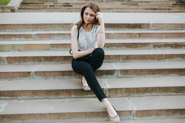 Obraz premium young girl with phone sitting on the stairs of an old house architecture
