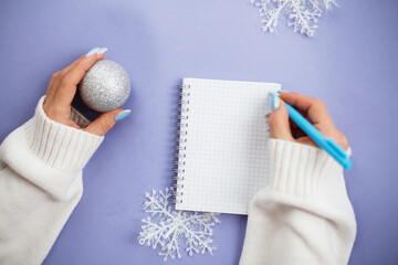 Woman hand with winter nails holding pen on notebook and writing wish list
