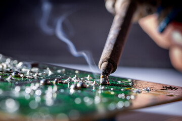 Technician repairs circuit board of television with iron soldering and tin wire, close up