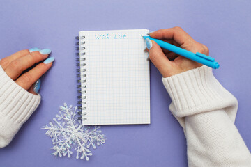 Woman hand with winter nails holding pen on notebook and writing wish list
