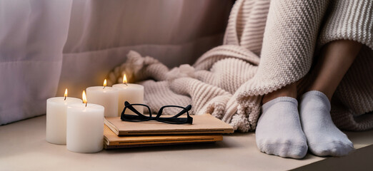 Candle cozy glasses in bed with book and blanket. Warm woolen sweater in cold autumn or winter...