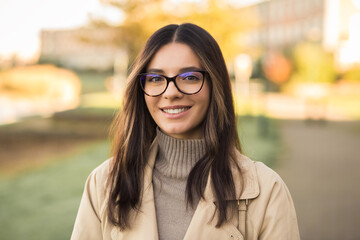 Close-up portrait of independent woman student 20s with amazing smile wearing glasses in the street