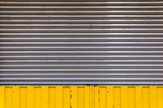 Horizontal old grey corrugated metal garage and store door with yellow frame