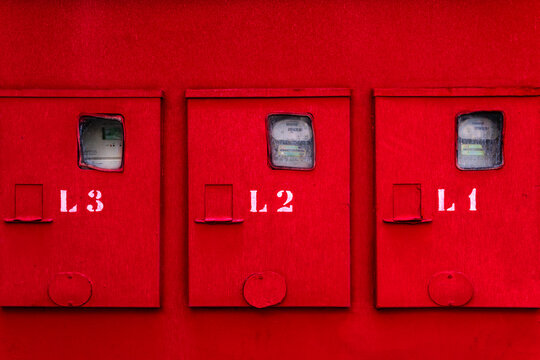 Red wall with with three numbered meter boxes.