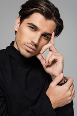 portrait of pensive model in black turtleneck posing isolated on grey