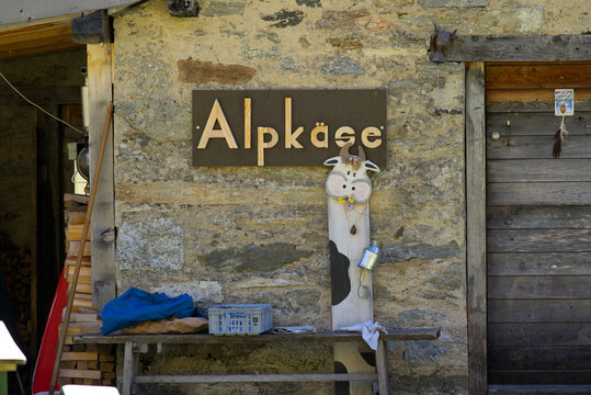 Sign with text alp cheese and cow sign at stone cabin at mountain hamlet Gletsch, Canton Valais, on a sunny late summer noon. Photo taken September 12th, 2022, Gletsch, Switzerland.