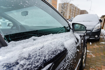 Doors and handles covered with snow and frost.Snowfall,winter driving,preparing for the trip.Black car coated in snow at cold weather.Side mirror and window are covered with snow.