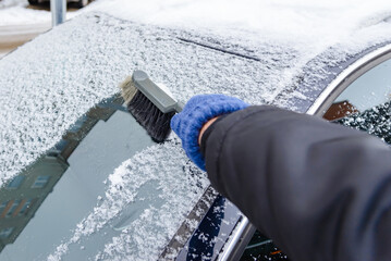 Frosty weather.Winter scene, human hand in glove.Man cleans snow from the car.A car covered with snow.