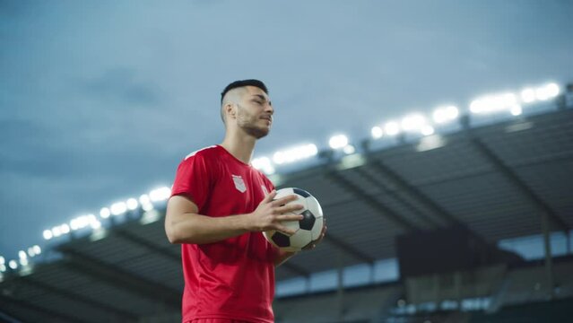 Football Match Championship: Portrait of Red Team Soccer Player Holding a Ball, Standing, Smiling. Professional Footballer, Future Champion Ready to Win Cup, Tournament. Medium Arc Shot