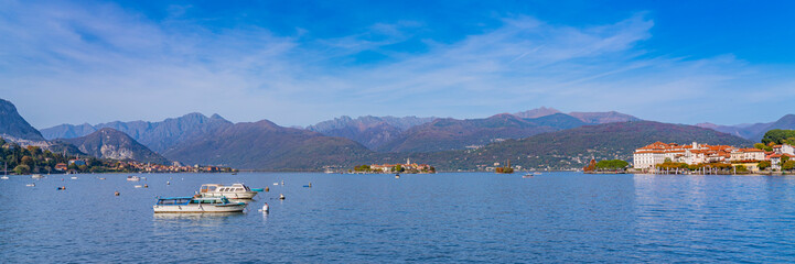 Fototapeta na wymiar Small wood boats at the lake Maggiore at Stresa, landscapes over the lake in the backgound the alps
