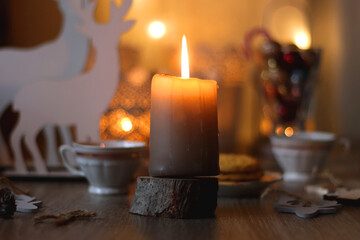 Two types of cookies, cups of tea or coffee, various Christmas decorations and lit candles. Cozy Christmas atmosphere at home. Selective focus.
