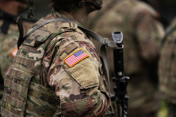 Fototapeta premium US Army soldiers uniform. Close up photo with the United States of America flag on a military soldier uniform with the gun next to it. Military industry detail concept photo.