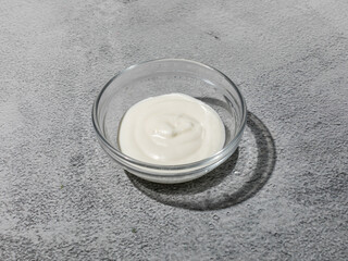 Classic sour cream white sauce in transparent glass bowl closeup