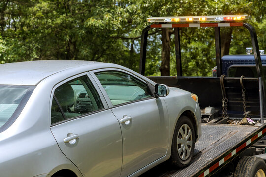 Working in towing service, loading damaged car that has been onto tow truck