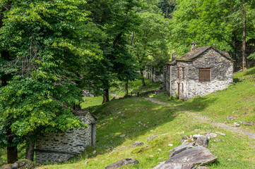 Fototapeta na wymiar Ruined stone houses and mills in an abandoned mountain village in the Alps