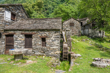 Stone watermill with wooden wheel in an abandoned mountain village in the Alps